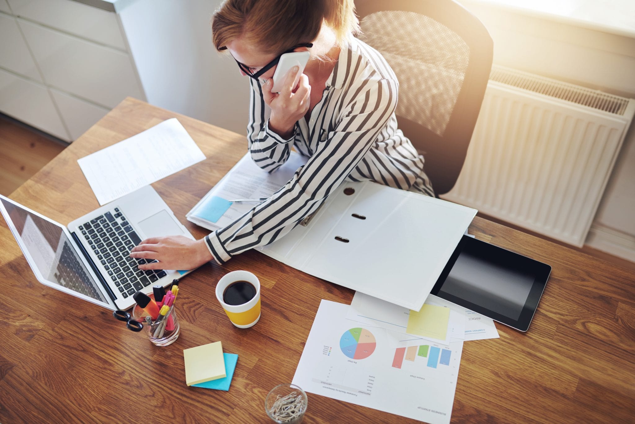 Successful businesswoman with an e-business working from an office at home telemarketing and taking orders over the phone or consulting with clients, high angle view